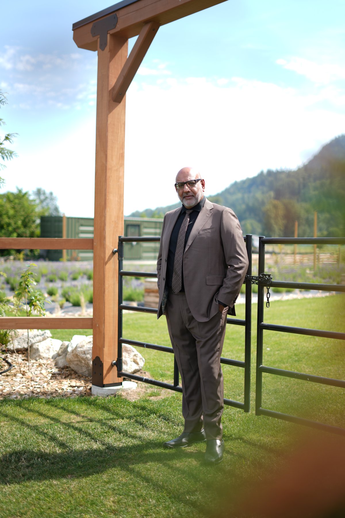 Tan three-piece suit framed by a cedar pavilion in British Columbia