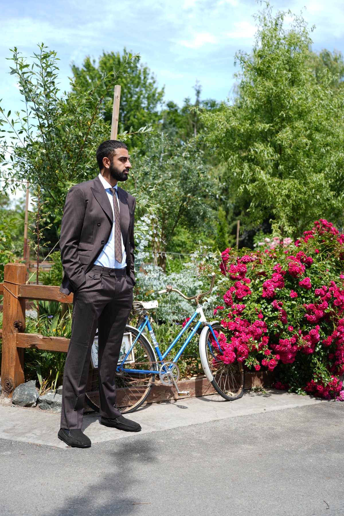 Brown bespoke suit against a wall of roses — garden editorial by Suited Booted & Co.