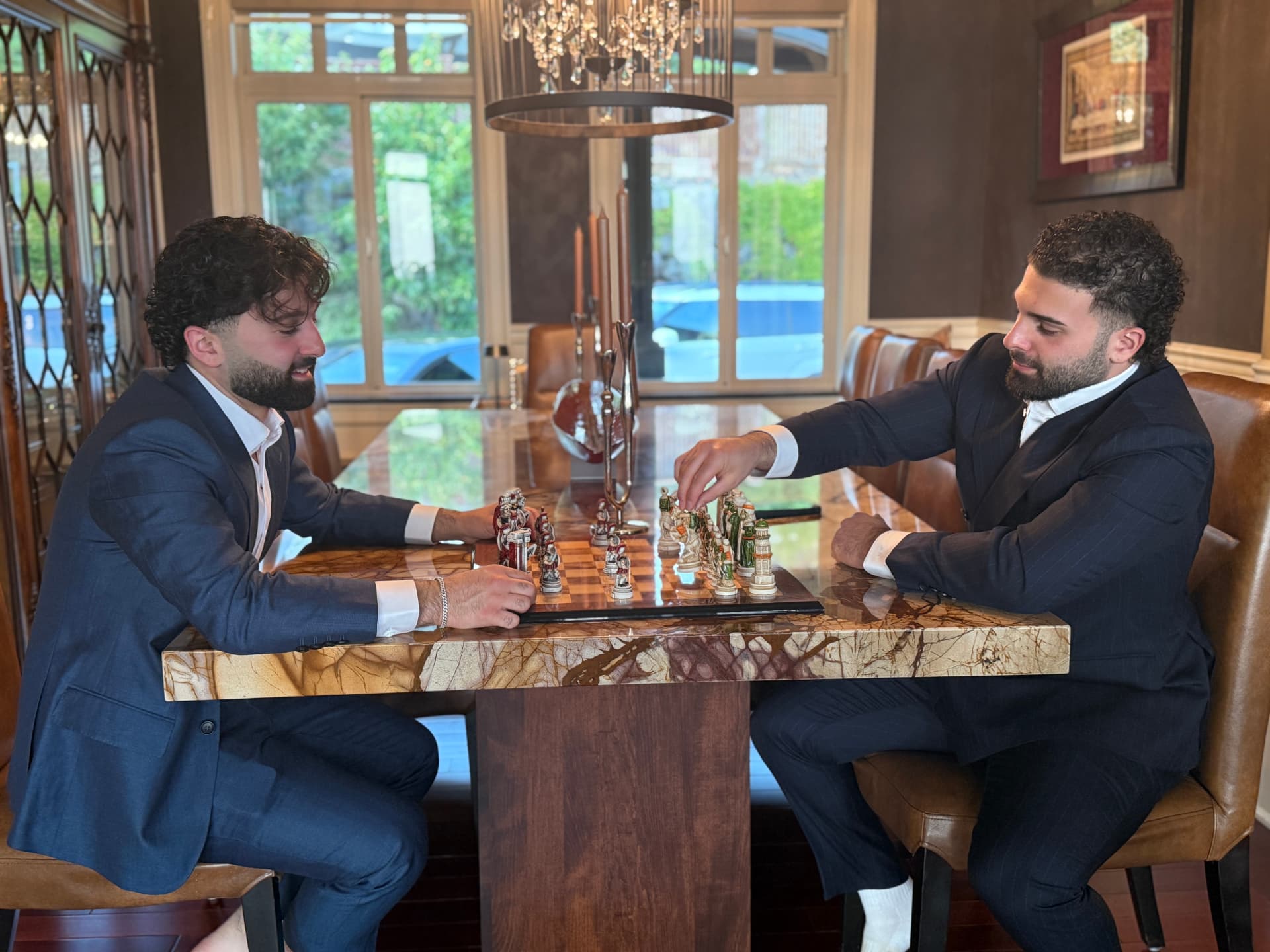 Two clients playing chess in bespoke suits at a private club